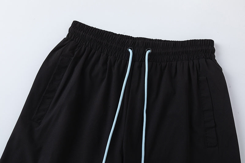 Black unisex drawstring shorts with blue letter graphic, elastic waistband, and side pockets - view 14