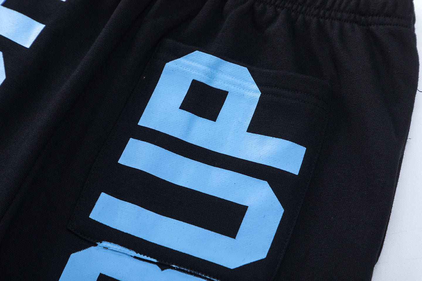 Men's black graphic shorts with light blue lettering, bottle-and-wings print, drawstring waist, and rear patch pocke - view 2