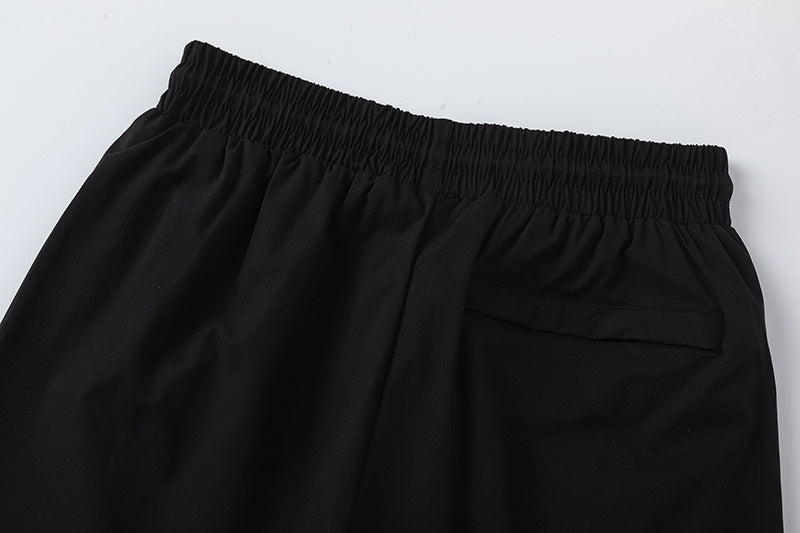 Black unisex drawstring shorts with blue letter graphic, elastic waistband, and side pockets - view 6