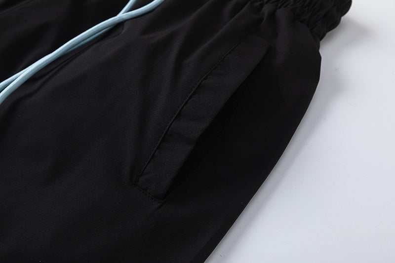 Black unisex drawstring shorts with blue letter graphic, elastic waistband, and side pockets - view 8