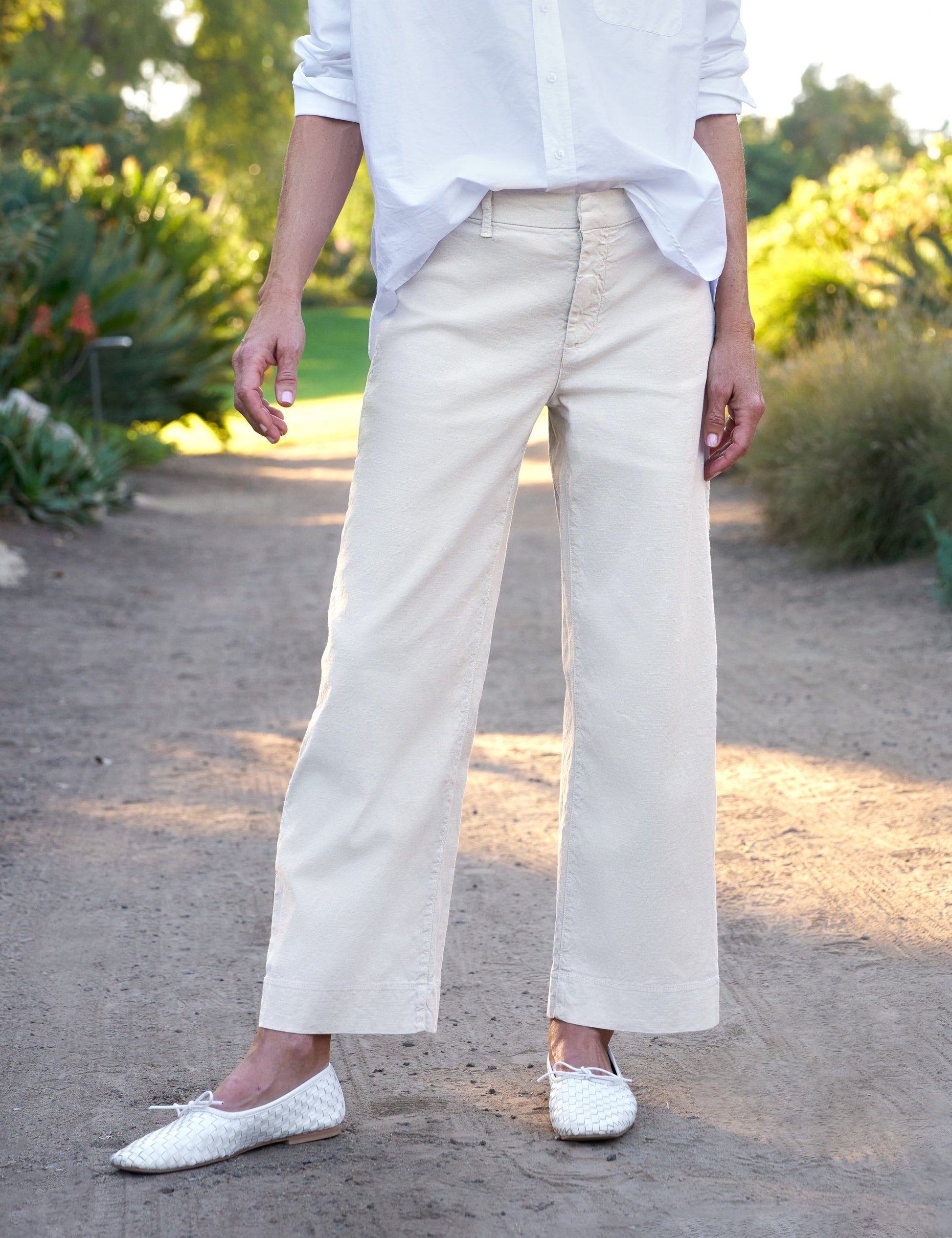 Person wearing beige pants and white shoes in a garden setting