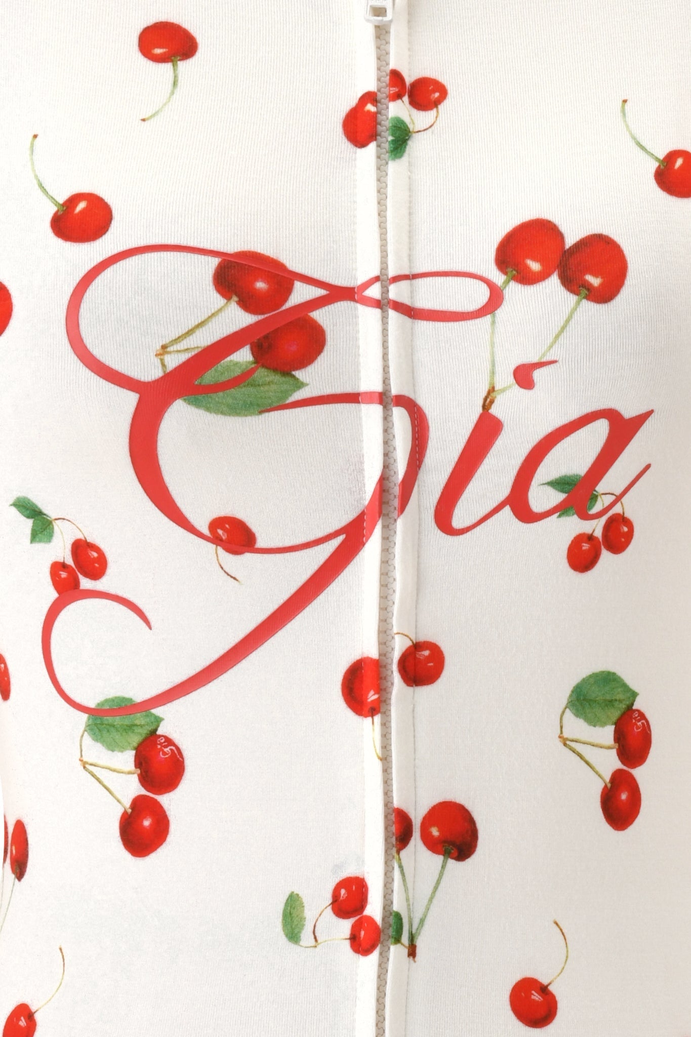 The BLARE HOODIE - CHERRY ON TOP from I.AM.GIA features white fabric with clusters of red cherries and green stems, a bold red "Gia" script, and a signature vertical zipper down the center.