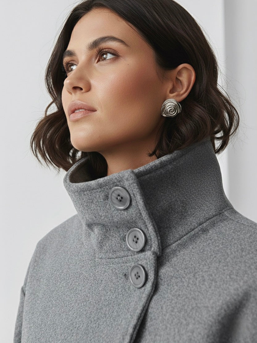 Black high-neck jacket with asymmetrical buttons and structured silhouette, featuring wide sleeves and a minimalist design for modern everyday styling.