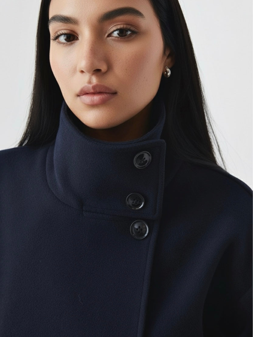 Black high-neck jacket with asymmetrical buttons and structured silhouette, featuring wide sleeves and a minimalist design for modern everyday styling.