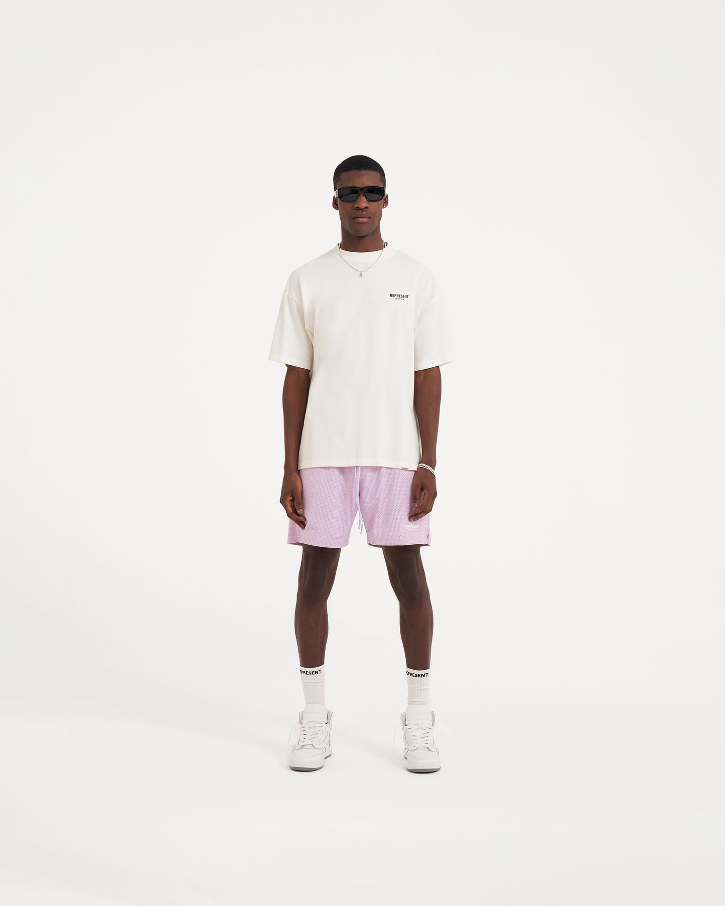 Man wearing an oversized white t-shirt on a plain white background | Represent Owners Club T-Shirt in Flat White | Short sleeve oversized t-shirt with graphic branding | Owners Club T-Shirts | Represent Clo